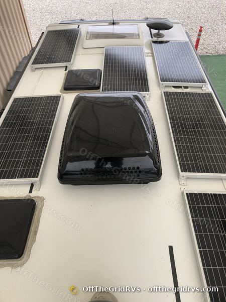 Overhead view of seven 100W solar panels laid out around the air conditioner and roof vents of the same Leisure Travel Vans Unity