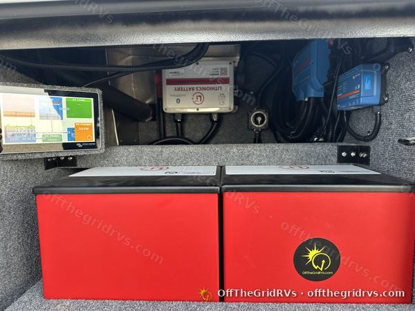 Two red Lithionics lithium modules in the battery compartment of a 2022 Newmar New Aire, with the external BMS, Victron SmartSolar charge controllers and a monitoring screen mounted above